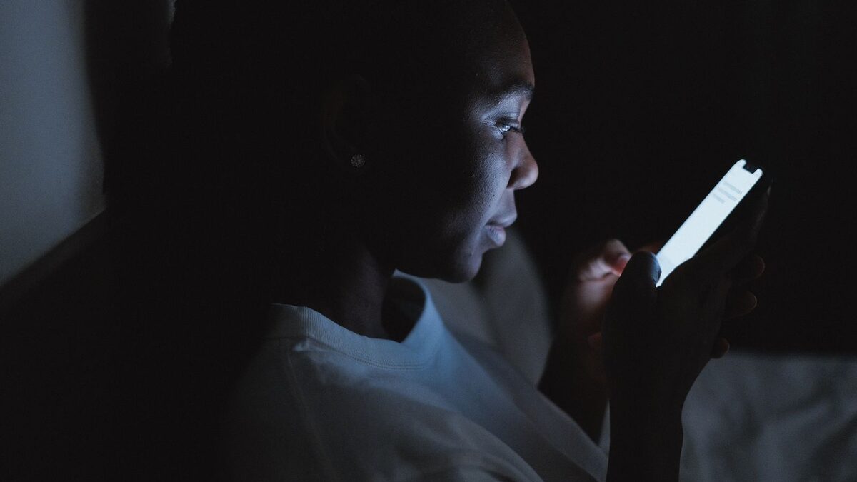 A person chatting privately on a phone late at night, lit only by the screen — the best AI sex chat sites of 2026