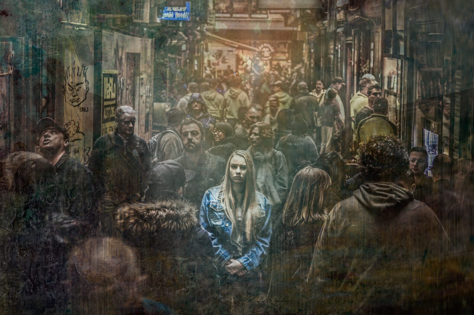 A person sits alone in a crowd, looking down — sadness and isolation in a public space