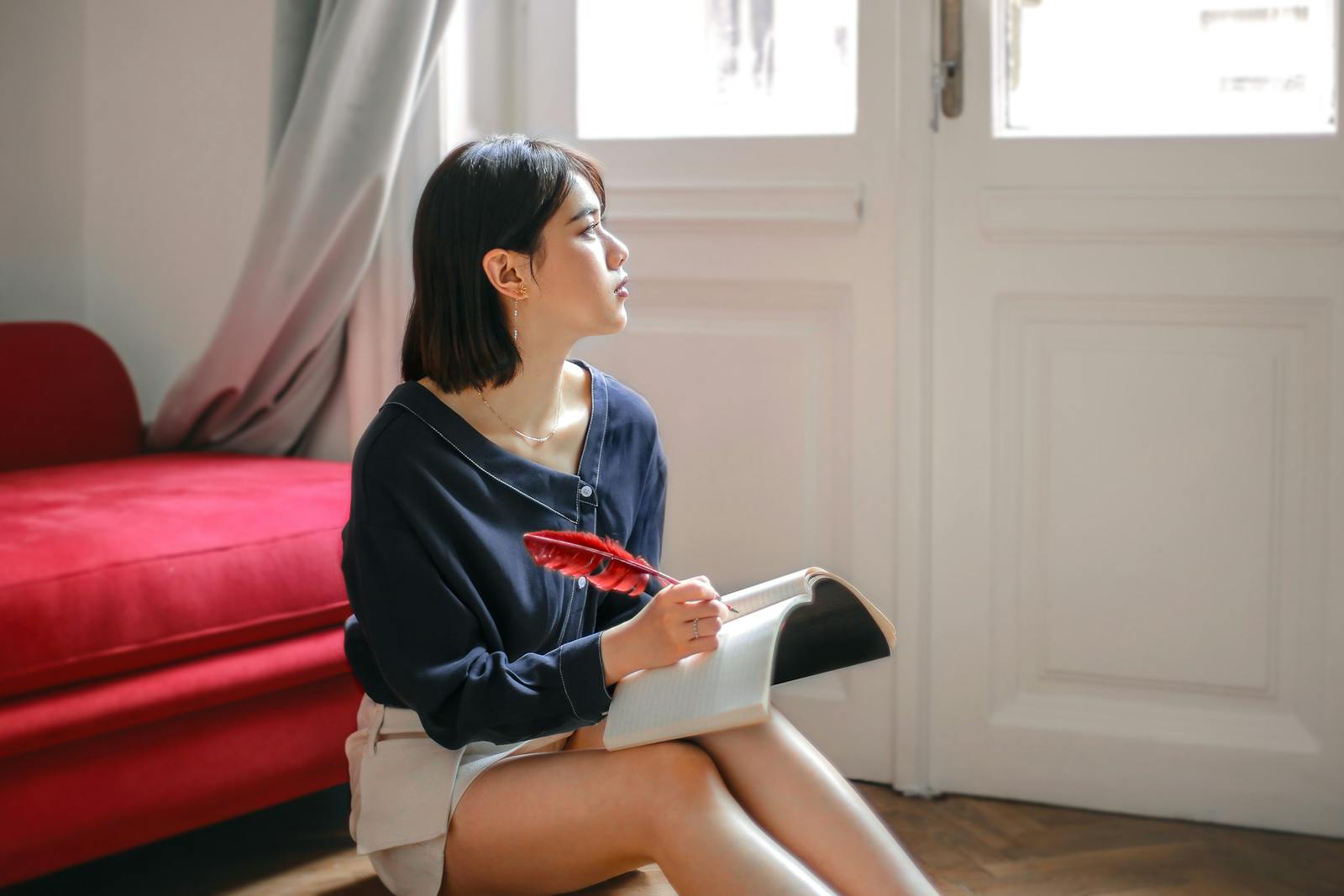 A young woman sitting by a window, writing thoughtfully in a notebook — the private, introspective work of figuring out what you actually feel
